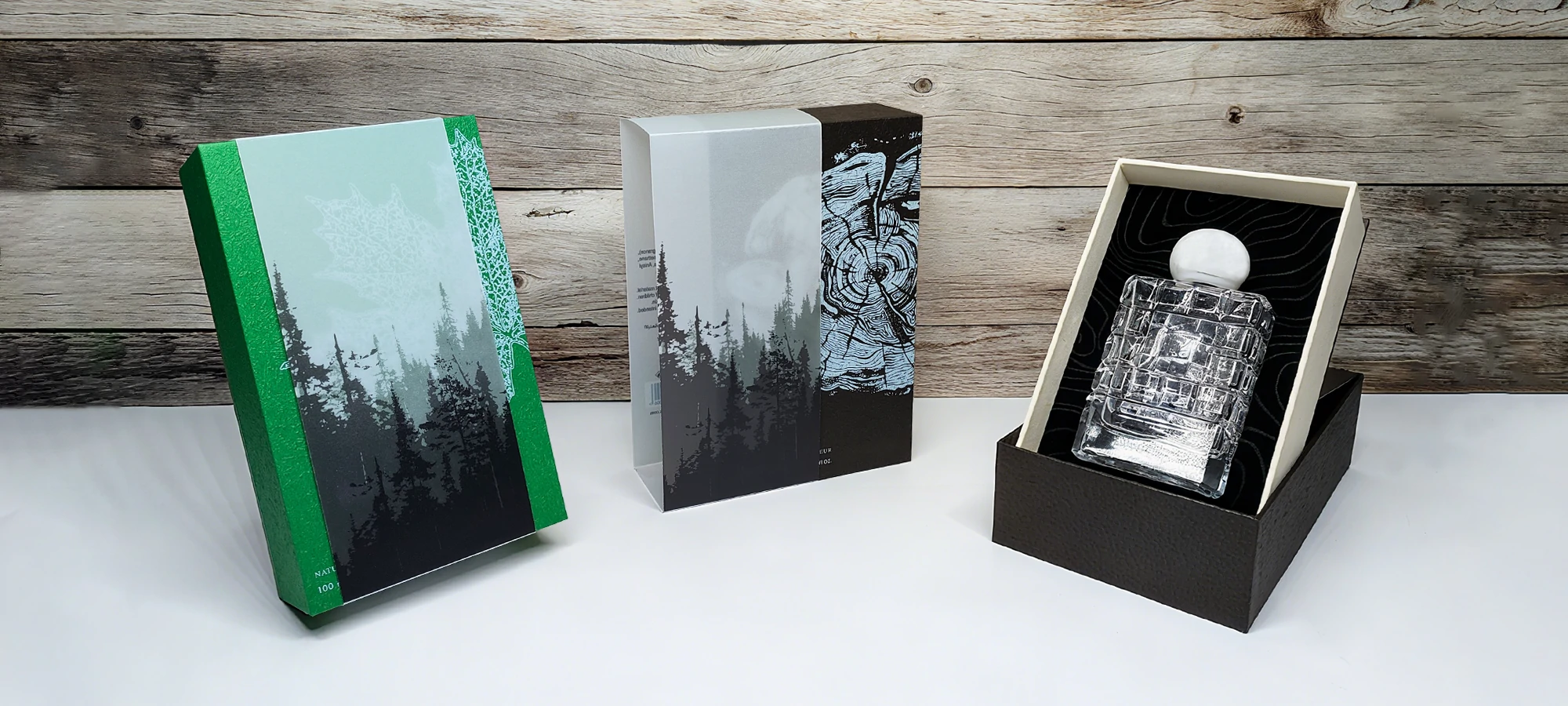 Green and black perfume cartons beside an open bottle presentation box